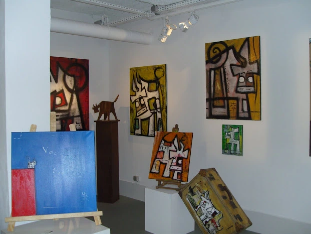 Intérieur d’une exposition au Musée en Herbe avec des œuvres accrochées aux murs et disposées sur des socles.